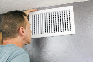 Man checking air vent to see if they need cleaning. 