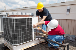 Two technicians working together to do maintenance on an HVAC system.